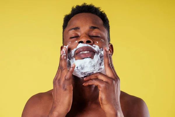 Hombre afroamericano con afeitadora y espuma de afeitar en la cara —  Fotos de Stock