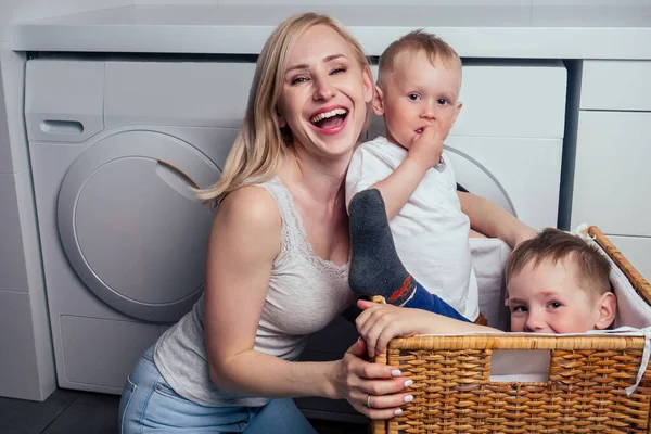 Mutlu aile evi hafta sonu sabah banyo yıkama makinesi. Anne ve küçük oğlu çamaşır odasında çamaşır yıkıyor. — Stok fotoğraf