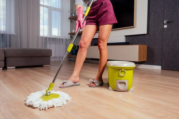 Vacker flicka golv dans med mopp och hink i aftonklänning och hälskor i en mysig lägenhet med en Tv i hallen.fru väntar på sin man hemma .rolig mamma rengöring företag — Stockfoto