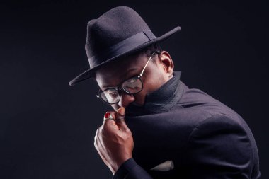 Siyah arka planda ceketli ve gözlüklü yakışıklı Afro-Amerikan melankolik çocuk. Gizem ve keder saklanıyor.