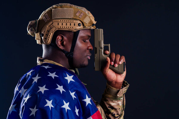american man in camouflage suit aiming with a pistol studio shot