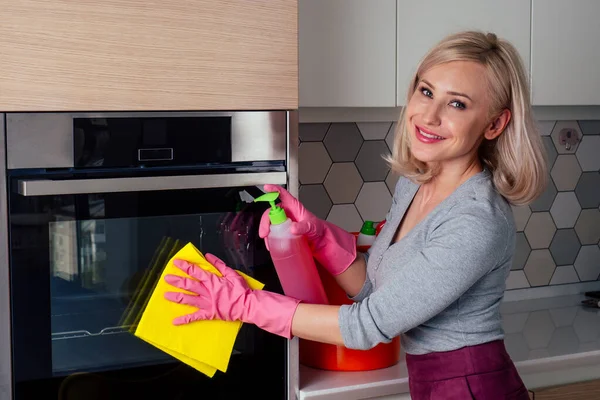 Νεαρή γυναίκα που καθαρίζει φούρνο στην κουζίνα — Φωτογραφία Αρχείου