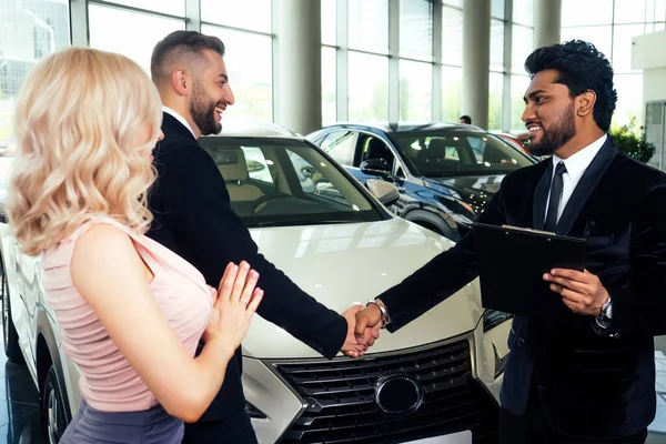 Bonito indiano vendedor mostrando luxo auto para rico família compradores no moderno showroom.husband e esposa escolher carro — Fotografia de Stock