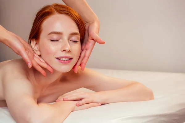 Pelirroja pelirroja mujer en spa consigue un masaje facial — Foto de Stock