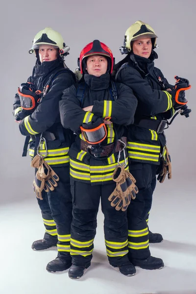 Retrato três homens bombeiros fortes em uniforme à prova de fogo estúdio de fundo branco — Fotografia de Stock