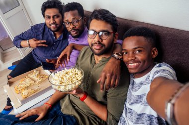 Dört Afro-Amerikalı arkadaş akıllı telefon kamerasında İtalyan pizzası ve ev partisinde patlamış mısırla selfie çekiyor.
