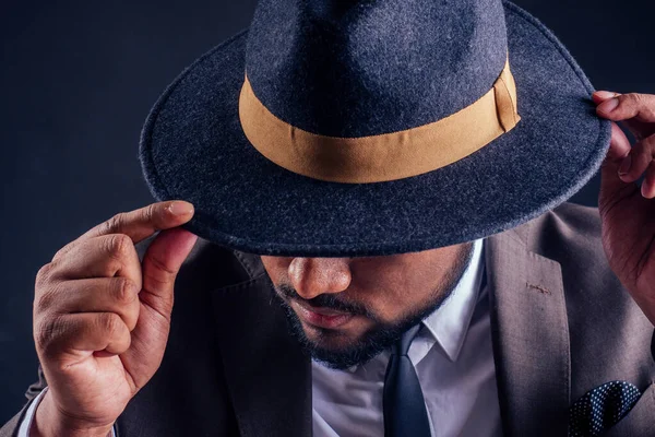 indian business man wearing hat and classic suit on black background in studio