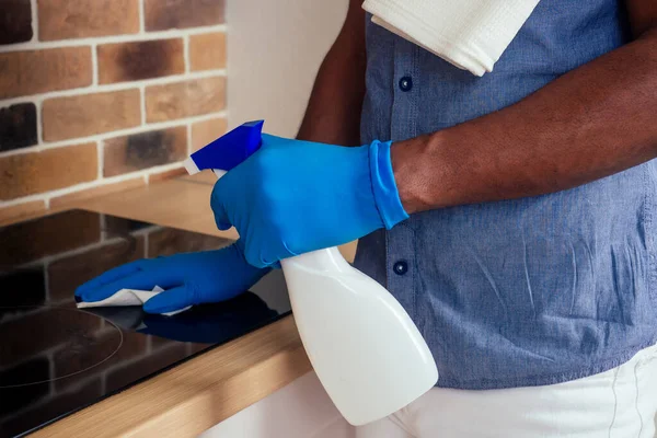 Αφρικανός άνδρας που καθαρίζει την κουκούλα κουζινών εστιών στο σπίτι, φόντο τούβλων — Φωτογραφία Αρχείου
