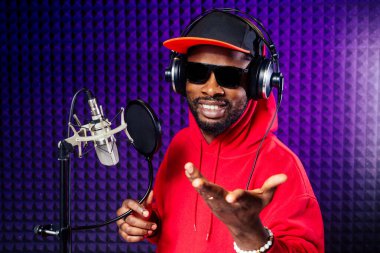 Şapkalı ve kapüşonlu kulaklıklı Afro-Amerikan erkek kulaklıkları hip hop şarkıları kaydediyor..