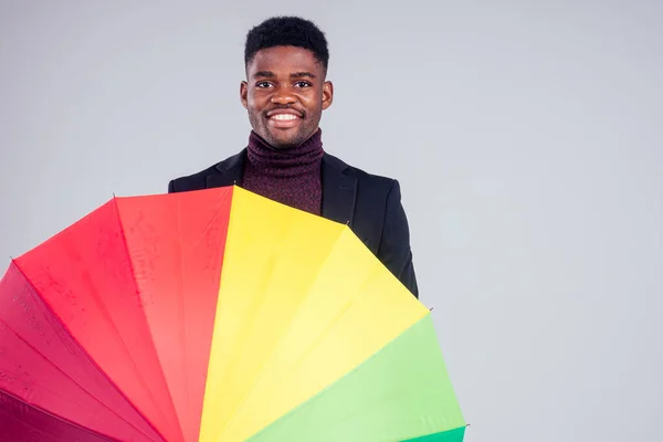 Homem de negócios sorridente em lã casaco terno com multi-colorido guarda-chuva estúdio de fundo branco — Fotografia de Stock