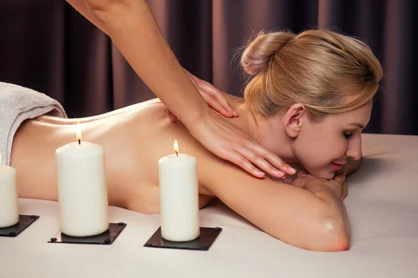 Vacker blond kvinna liggande massage spa bredvid ljus eld — Stockfoto
