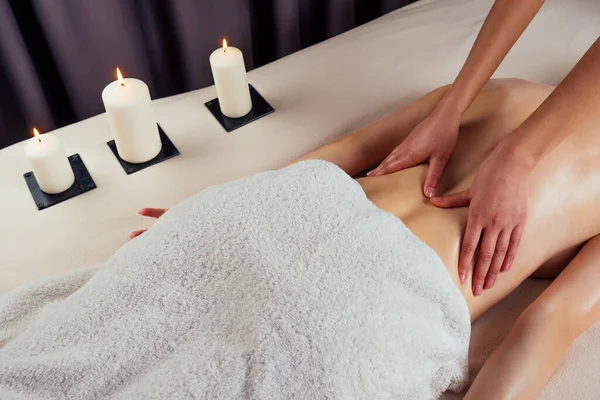 Hermosa rubia femenina relajación en el salón de spa con masajista profesional hombro cuerpo al lado del fuego de la vela — Foto de Stock