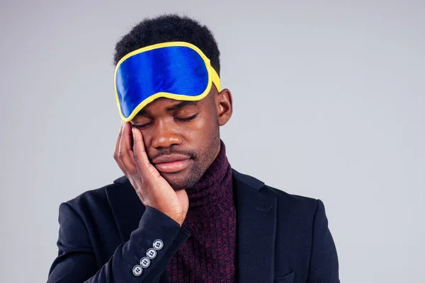 Sleepy businessman wearing an eye mask white background studio