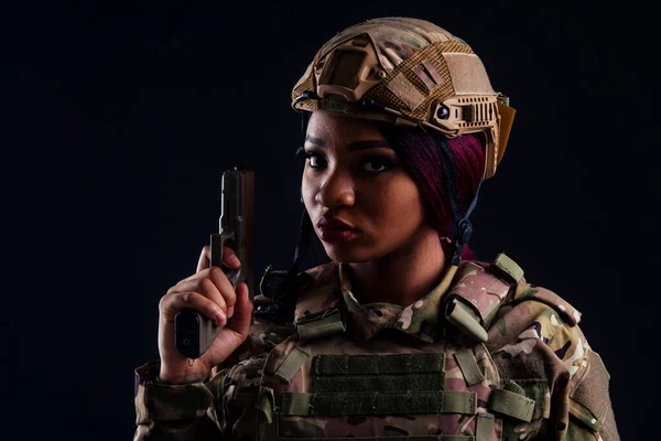 Young latin indian woman soldier with gun studio black background