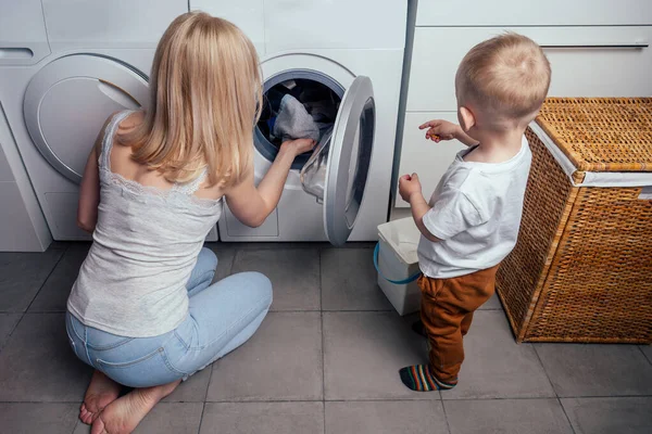 Felice famiglia casa week-end mattina bagno lavatrice madre e piccolo figlio in lavanderia Lavatrice lavato i vestiti — Foto Stock