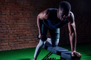 Genç kaslı Afrikalı Amerikalı adam şınav çekiyor ve başka tarafa bakıyor.