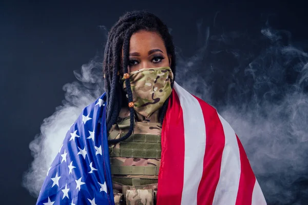 afro american army latin soldier in camouflage clothes dreadlocks makeup and big lips on black background smoke in studio with american flag,independence day usa 4th of july