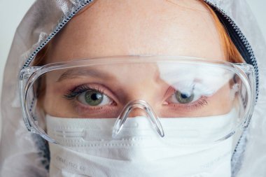 Kimyasal koruma maskeli, gözlüklü ve eldivenli virolog kadın laboratuarda potansiyel aşı taşıyor.