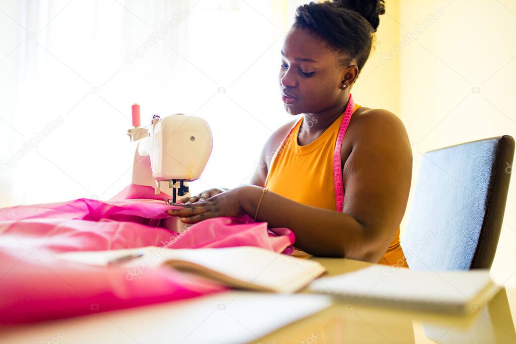 mixed race woman seamstress sews clothes in the house