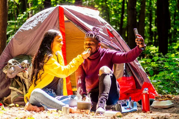 Afro americano misto casal estabelecendo instalação de uma barraca e tendo um tempo de descanso ao ar livre — Fotografia de Stock
