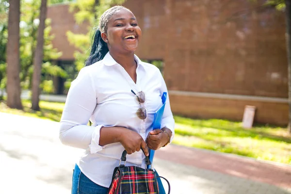 Schöne lächelnde junge Afrikanerin in weißem T-Shirt und in der Hand ein Werbebuch — Stockfoto