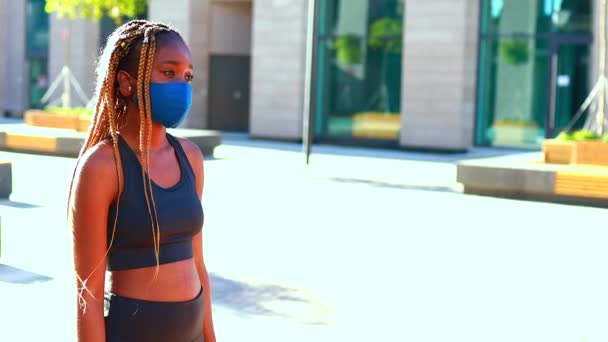 Uma menina afro snotty fica na rua usando uma máscara — Vídeo de Stock