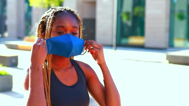 Sports Afro woman stands in a mask on the street in a tracksuit and wears a medical mask — Stock Video