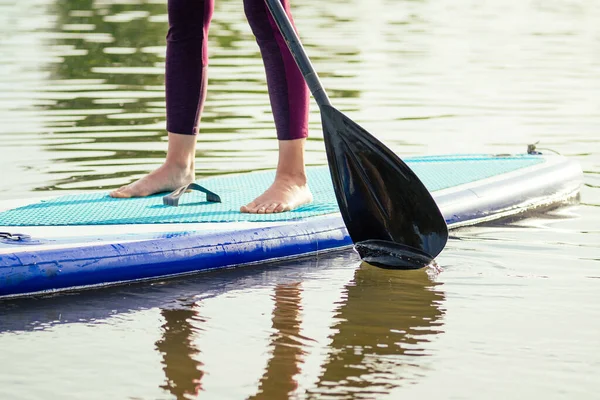 Levez-vous paddle embarquement sur un lac de mer calme, gros plan des jambes et éclaboussures d'eau — Photo