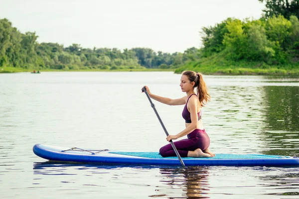 Femme sur la planche à soup dans la nature le soir — Photo