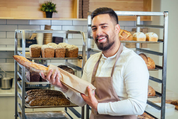 Cheerful baker delivering bread to client in store