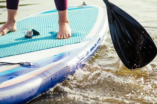 Wstań paddle boarding na spokojnym jeziorze morskim, zbliżenie nóg i wody splash — Zdjęcie stockowe