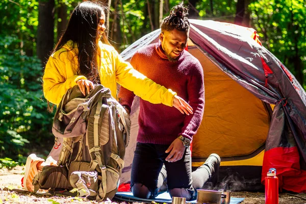 Afro americano mixto raza pareja estableciendo instalación un tienda de campaña y tener un descanso al aire libre — Foto de Stock