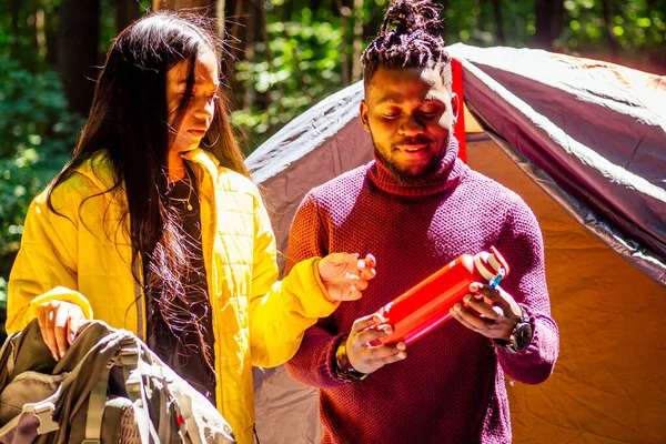 Afro americano misto casal estabelecendo instalação de uma barraca e tendo um tempo de descanso ao ar livre — Fotografia de Stock