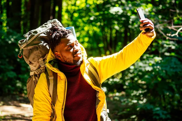 Africano americano masculino em casaco amarelo olhando para o mapa de localização do telefone on-line — Fotografia de Stock
