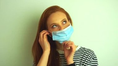 Genç kadın koruyucu beyaz tıbbi maske takıyor, tıbbi eldiven ve gözlük takıyor ve koronavirüs salgınına hazırlanıyor.