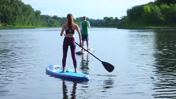 ผู้ชายและผู้หญิงในความรัก ยืนขึ้น paddlers เพลิดเพลินกับวันฤดูร้อน — วีดีโอสต็อก