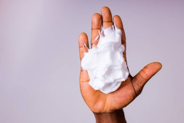 Afrikalı adam stüdyoda beyaz arka planda ıslak sabun tutuyor ve gösteriyor.