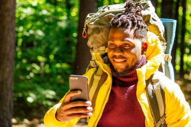 Sarı ceketli Afro-Amerikan erkek. İnternetteki telefon yeri haritasına bakıyor.