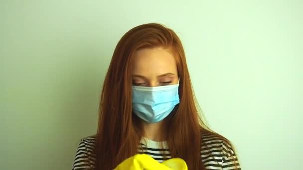 Mladá žena nosí ochrannou bílou lékařskou masku, nasazuje si lékařské rukavice, připravuje se na epidemii koronaviru — Stock video