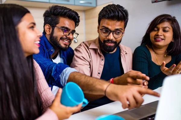 रसोई में भारतीय चार लोग लैपटॉप पर देख रहे हैं और होमवर्क दूरी सीखने पर चर्चा कर रहे हैं — स्टॉक फ़ोटो, इमेज