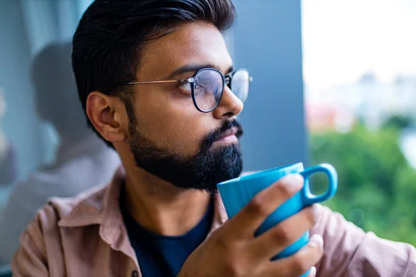 Homem árabe em vestido casual holning uma xícara azul e olhando sonhadamente — Fotografia de Stock