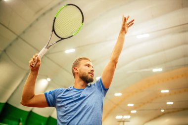 Eğitmen ya da koç içeride tenis oynamayı öğretiyor.