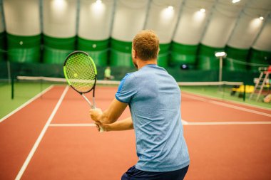 Eğitmen ya da koç içeride tenis oynamayı öğretiyor.
