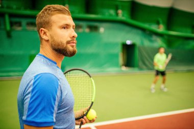 Eğitmen ya da koç içeride tenis oynamayı öğretiyor.