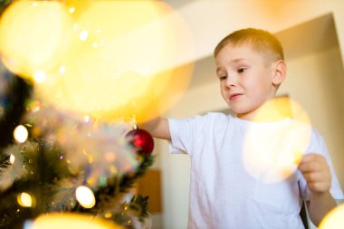 Koronavirüs nedeniyle karantinada Noel ağacını süsleyen çocuk.