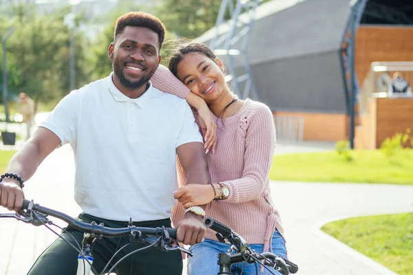 Riendo pareja joven montando bicicletas en el centro de la ciudad — Foto de Stock