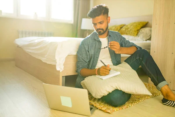 Indiana barbuda masculino sentado no chão e fazendo cálculos financeiros negócios on-line em novo apartamento — Fotografia de Stock