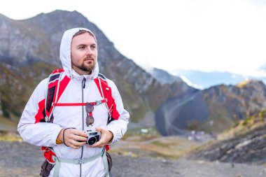 Genç, neşeli fotoğrafçı eski moda bir kamerayla dağlarda fotoğraf çekiyor.