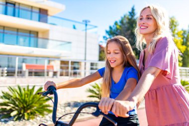 Anne ve babası çocuklara tropikal plajda araba sürmeyi öğretiyor.