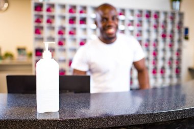 Afro-Amerikalı resepsiyonist çalışma masasını sterilize ediyor.